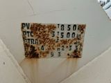 a rusted sign on the side of a building