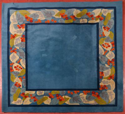 une photo d'un tapis orné d'une bordure bleue et de baies rouges