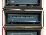 three blue train cars sitting in a cardboard box on a white surface