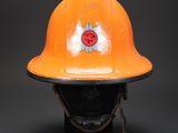 an orange fireman ' s helmet on display against a black background