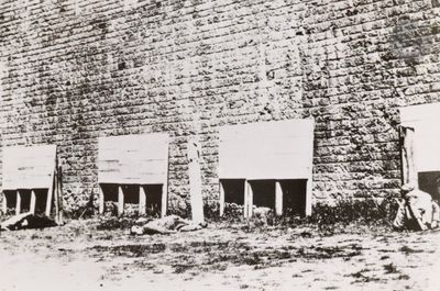 a black and white photo of a group of people standing in front of a brick wall