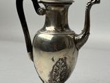 a silver tea pot with a black handle on a table