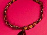 a brown beaded bracelet with a heart charm on a pink background
