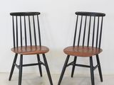 une paire de chaises noires et en bois devant un mur blanc