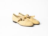 chaussures en cuir beige ornées de nœuds sur le bout, sur fond blanc