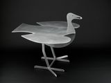 a glass bird that is sitting on a metal stand