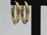 pair of gold tone hoop earrings on a black stand
