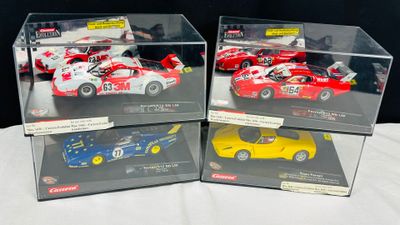 Quatre modèles réduits de voitures différents sont exposés dans une vitrine posée sur une table
