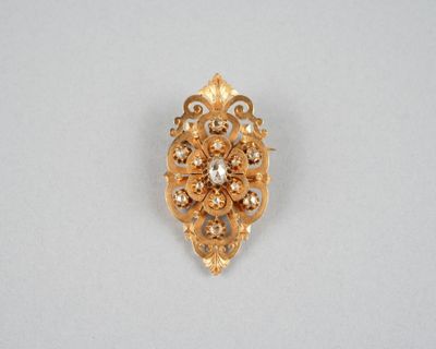 gros plan d'une broche en or sur une surface blanche