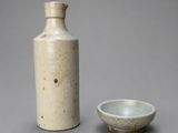 une image représentant un vase blanc et un petit bol posés sur une surface grise