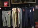 many different colored pants hanging on a rack in a store
