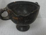a black bowl with a handle on a white surface