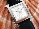 a close up of a watch with a shell in the background