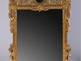 un miroir avec un cadre doré et une horloge dessus