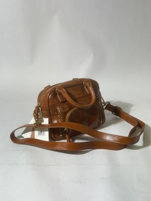 a brown purse with a strap and a tag on it