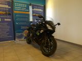 une moto noire garée devant un panneau bleu et blanc