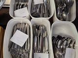 de nombreux types d'argenterie rangés dans des récipients posés sur la table