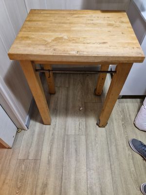 une petite table avec un plateau en bois, dans un coin de la pièce