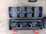 une mallette à outils noire, contenant des outils, posée par terre