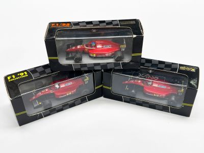 trois voitures rouges se trouvent dans une boîte posée sur une surface blanche