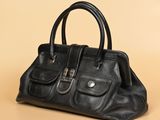 un sac à main noir posé sur une surface beige