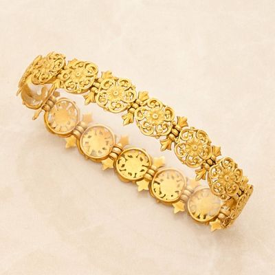 a close up of a gold bracelet on a white surface