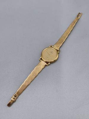 gros plan d'une montre en or sur une surface blanche