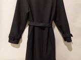 a black coat hanging on a wall with a white curtain in the background