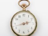 a gold and green pocket watch on a white surface