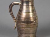 a silver pitcher sitting on a table with a gray background