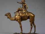 bronze statue of a man riding a camel with a hat on his head