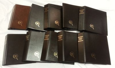 several books are lined up on a bed with a white sheet