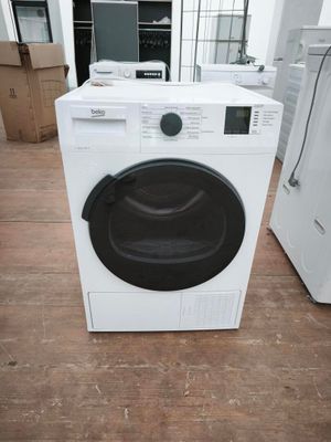 une machine à laver blanche posée à même le sol dans une pièce