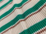 a close up of a green and white striped blanket on a bed