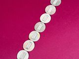 a close up of a silver bracelet on a pink surface