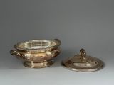 two silverplated dishes with lids and lids on a table