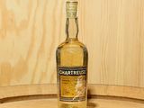 une bouteille de Chartreuse posée sur un tonneau