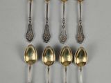 six cuillères en argent ornées de motifs élaborés, posées sur un fond gris