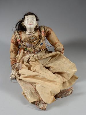 a close up of a doll sitting on a white surface