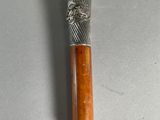 un bâton en argent et en bois surmonté d'un nœud