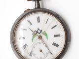 une vieille montre de poche accrochée à un mur blanc