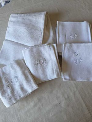 four white towels with embroidered monograms on them on a bed