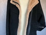 La veste est noire et beige, avec une doublure en imitation fourrure.