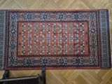 a rug on a wooden floor with a chair in the background