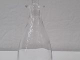 a clear glass bottle with a handle on a white table