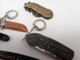 several different types of pocket knives and key chains on a white surface