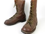 pair of brown boots with green laces on them on a white surface