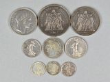 Plusieurs pièces de monnaie différentes sont disposées en rangée sur une surface blanche