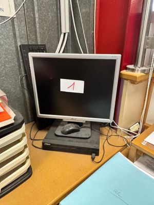un écran d'ordinateur posé sur un bureau, à côté d'une pile de livres