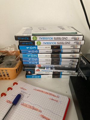 une pile de DVD posée sur un bureau, à côté d'un ordinateur portable